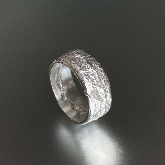 Sand Casted Silver ring with textured surface on a dark background