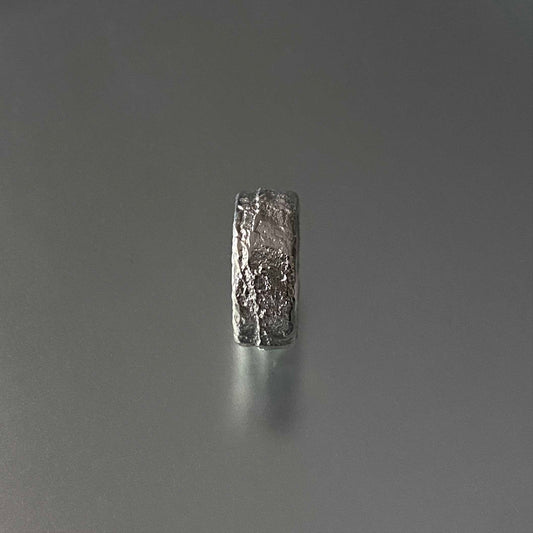 Sand Casted Silver ring with a textured surface on a gray background