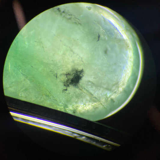 Close-up of an emerald gemstone under magnification on a dark background
