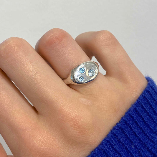 Silver ring with three topaz  stones on a finger against a white background. Daras Space