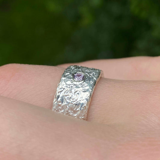 Silver ring with a pink sapphire on a finger