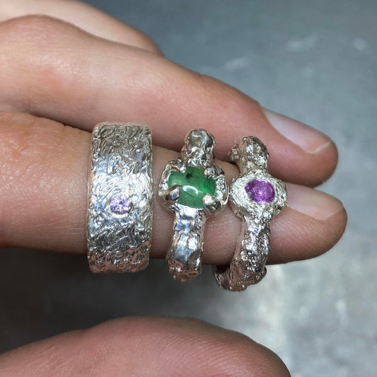 Close-up of a hand wearing three silver rings with gemstones. Daras Space