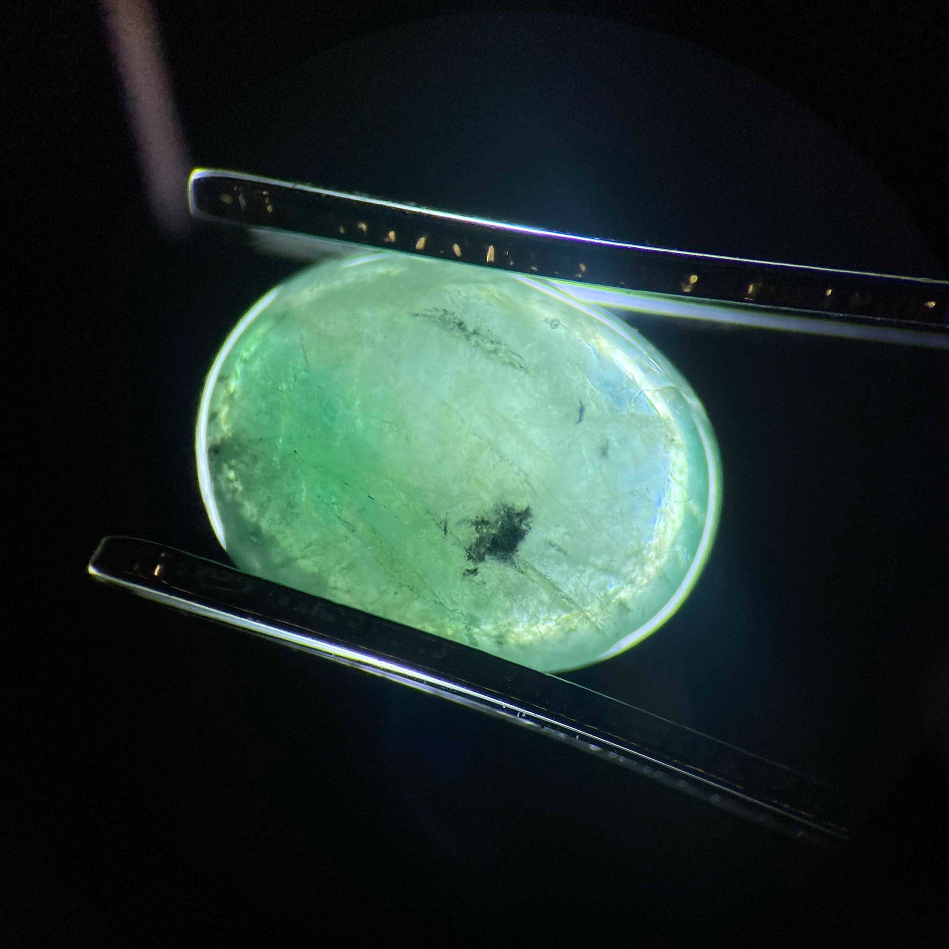 Close-up of a emerald stone under a magnifying glass on a dark. Daras Spacebackground