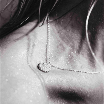 Silver necklace with a foil texture pendant on model. daras space