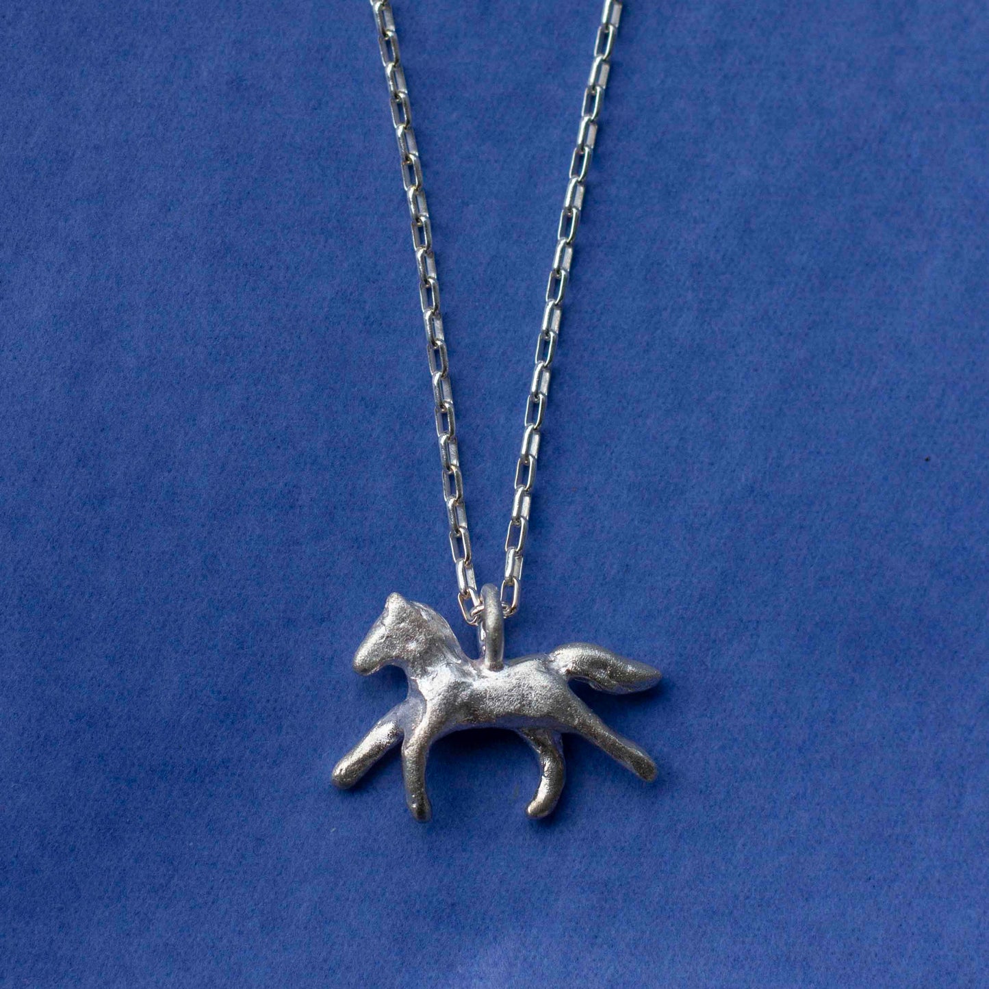Silver horse pendant necklace on a blue background
