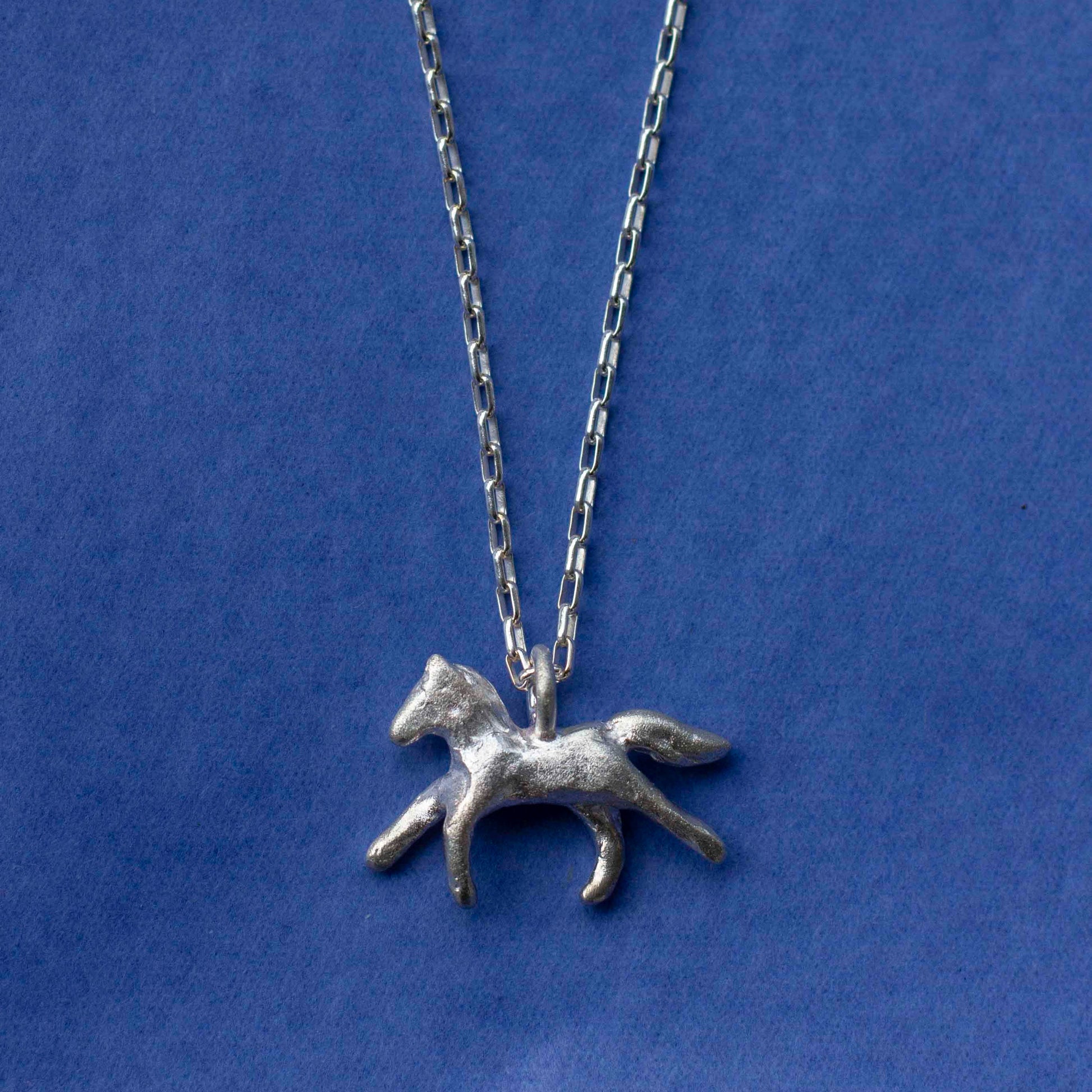 Silver horse pendant necklace on a blue background
